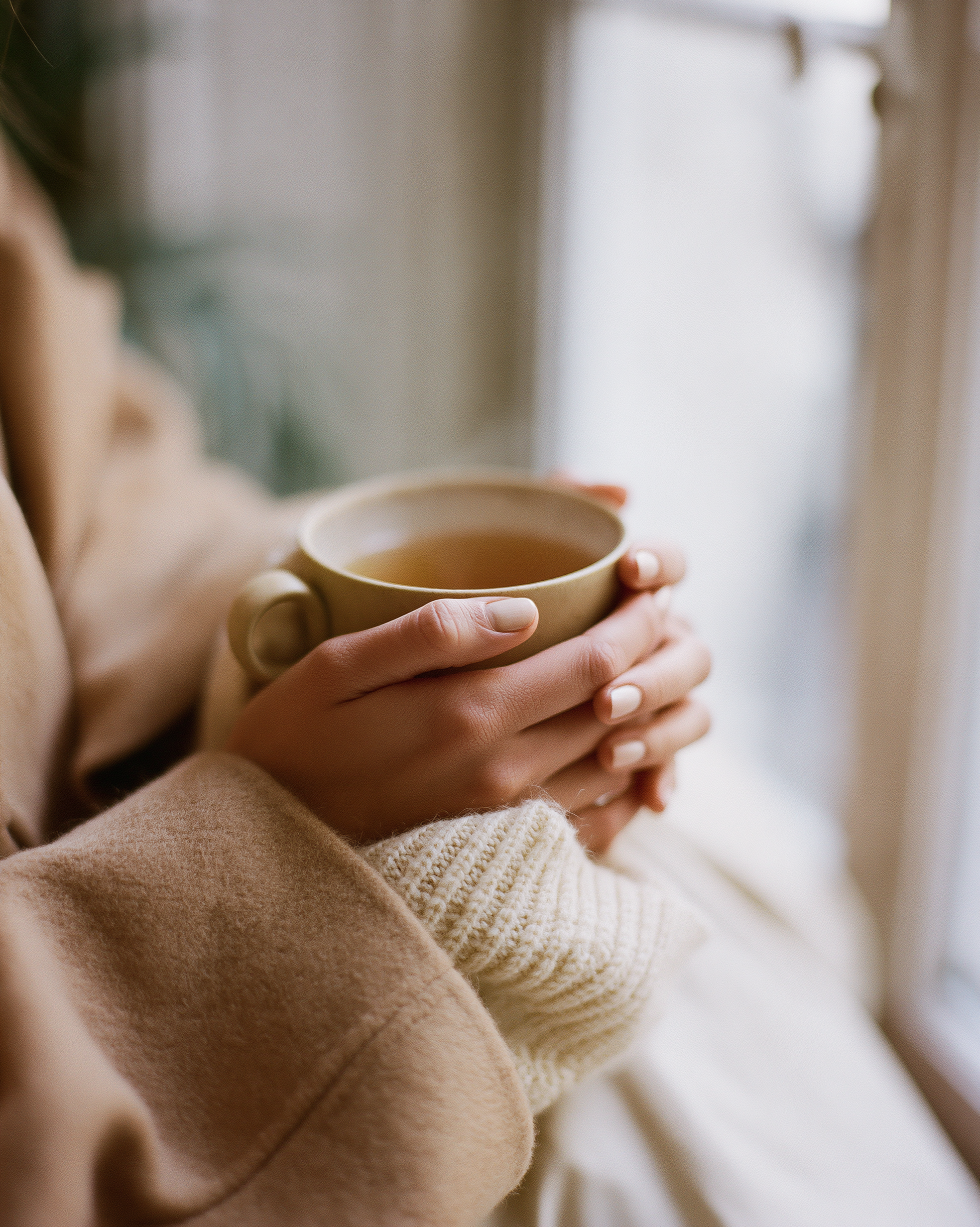 Mains tenant une tasse de thé, manteau cachemire Atelier MAUDÉ